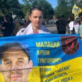 Аліна тримає прапор із портретом свого безвісти зниклого чоловіка. Фото з особистого архіву Аліни